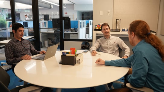 three it workers sitting at a table discussing compliance strategy 